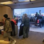 Volunteers putting multiple folded tables into a pickup truck