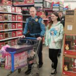 State troopers and a volunteer with a cart full of pink girl toys