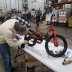 A volunteer putting training wheels on a red bike