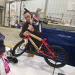 A volunteer putting the handle bars on a red bike