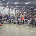 Multiple tables with volunteers building bikes