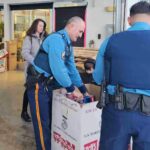 A state trooper with a box that says Toys for Tots.