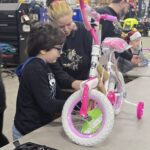 A child and mother assembling a bike