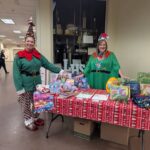 2 elves behind a table of donated items