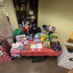 An elf next to a table with a lot of donations