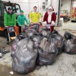 Santa with 3 people with about 9 trash bags filled with donations.